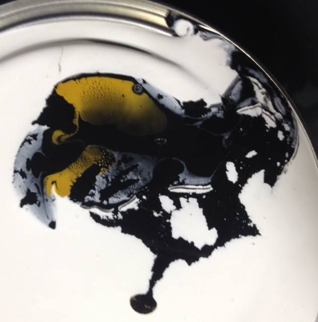 A white plate with black and yellow paint on it