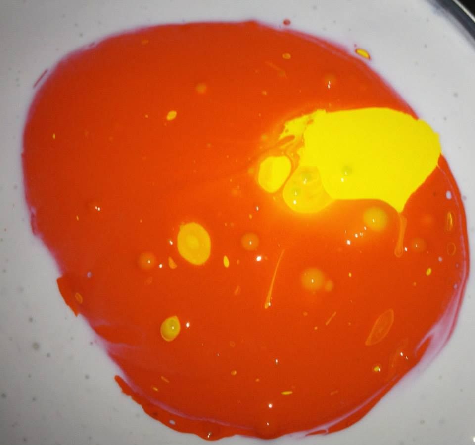 A close up of a red and yellow liquid on a white surface.