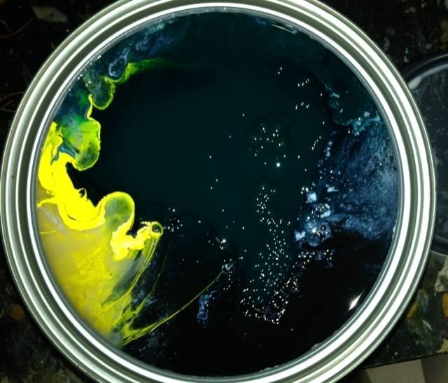 A can of blue and yellow paint is sitting on a table