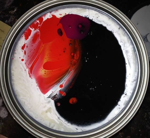 A can of paint has red and black paint in it