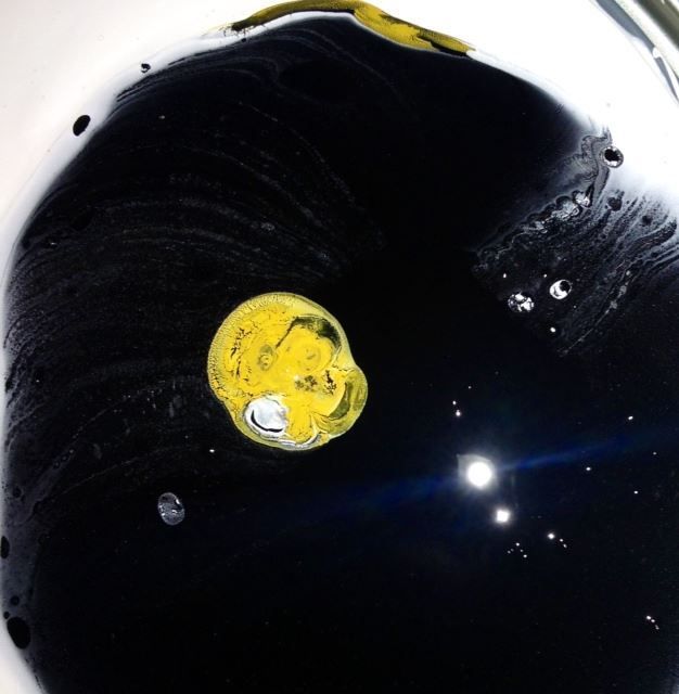 A yellow smiley face is floating in a black liquid