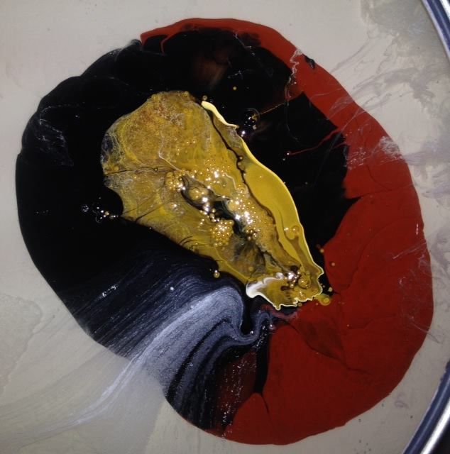 A close up of a painting with black red and yellow paint