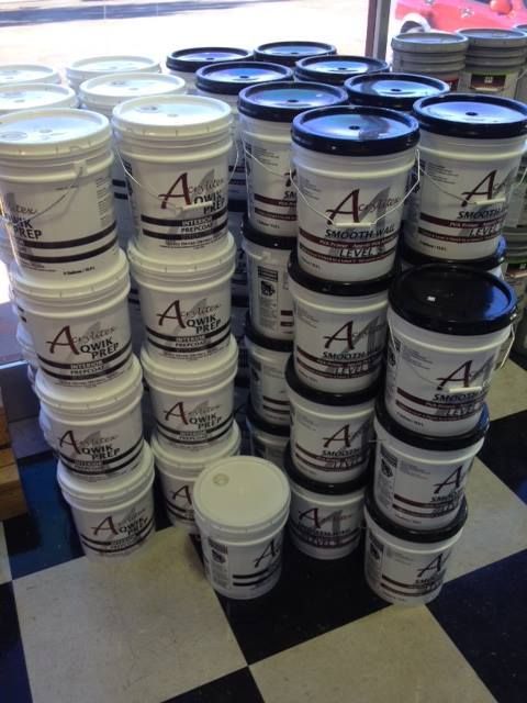 Buckets of acrylic paint are stacked on top of each other