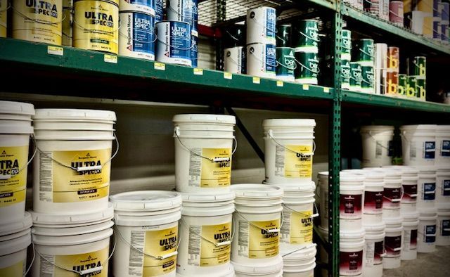 Buckets of paint are lined up on shelves in a store