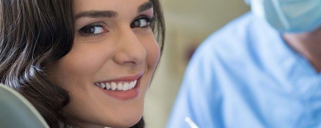 Smiling woman in close-up, with a blurred person in a blue shirt in the background