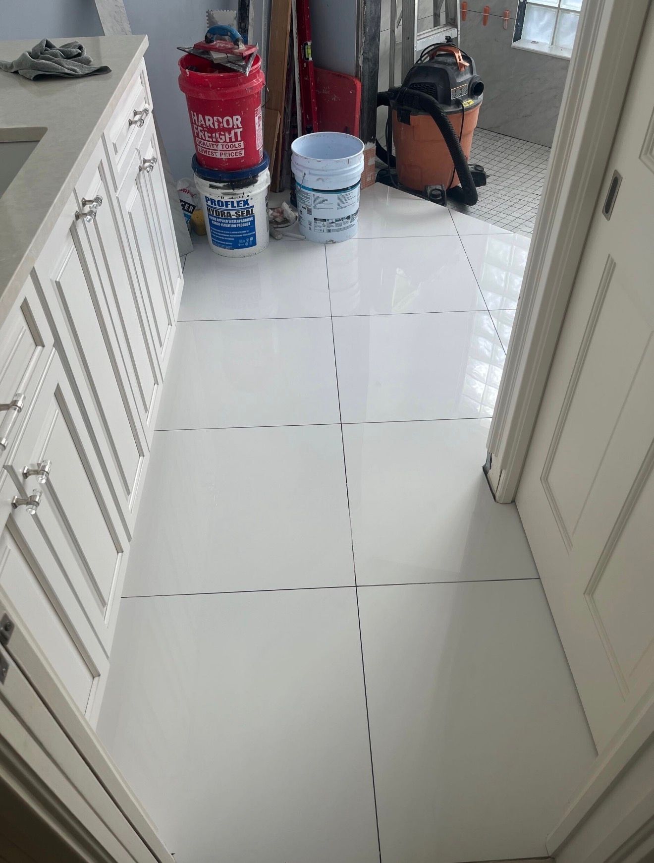Tiled hallway with paint buckets, a backpack, and cleaning supplies at the far end.