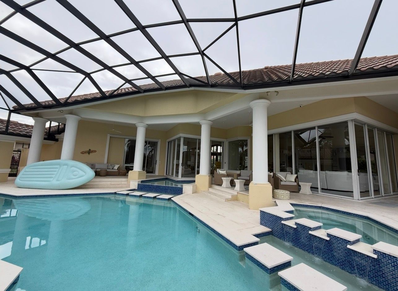 Luxury poolside patio with covered pergola, white columns, lounge chairs, and blue-tiled pool.