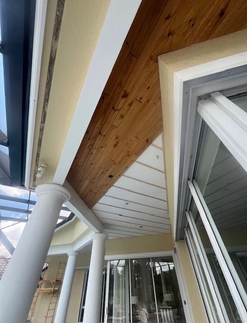 Covered patio with white columns, wood-paneled ceiling, and sliding glass doors