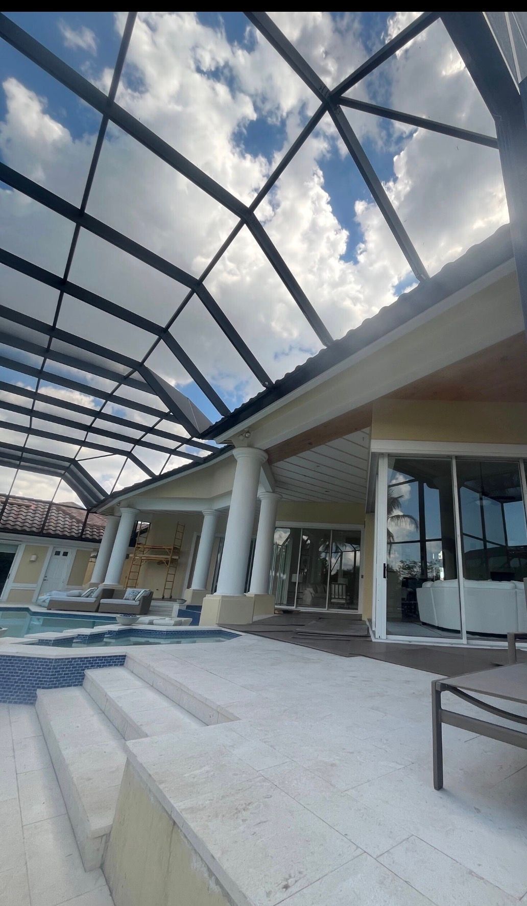 Covered outdoor mall walkway with glass canopy, columns, benches, and storefronts