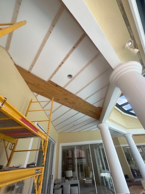Interior with vaulted ceiling, exposed beams, yellow scaffolding, white columns, and large glass doors