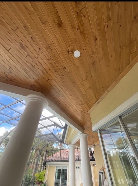 Covered patio with white columns, wood-paneled ceiling, and sliding glass doors.