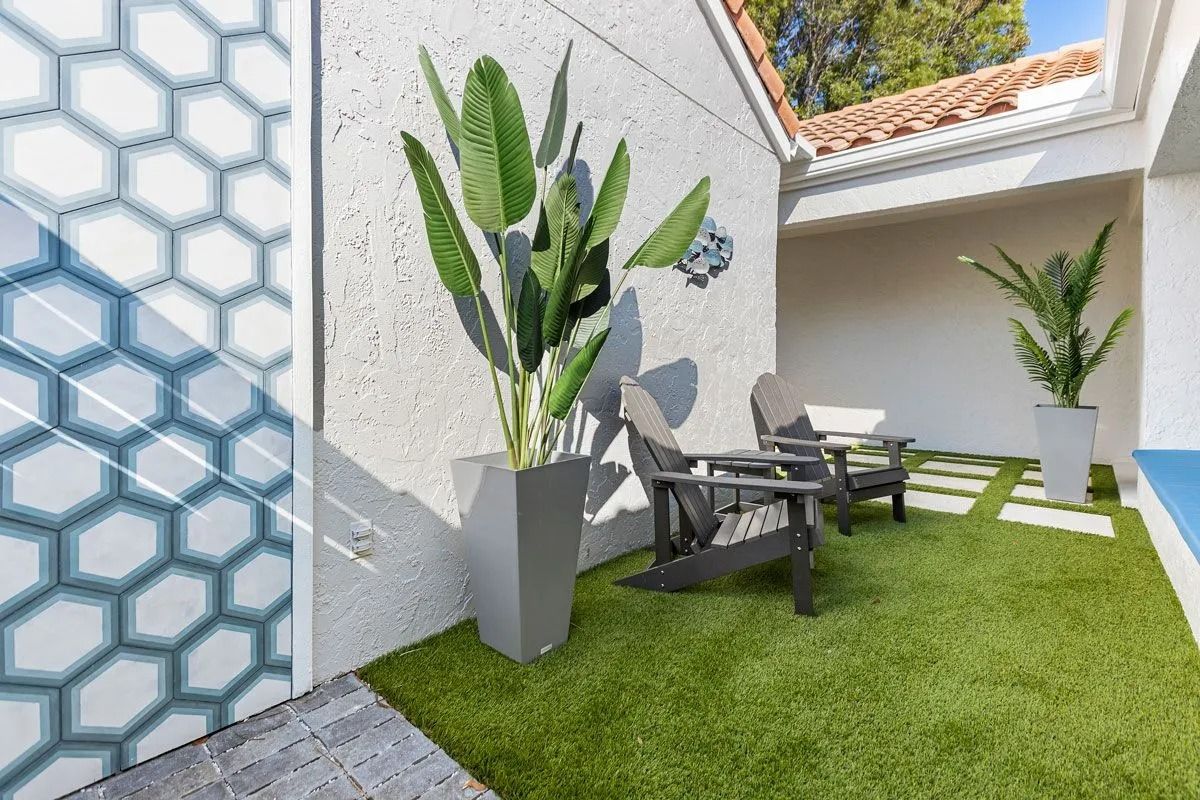 Outdoor seating area with artificial turf, plants, and decorative wall tiles.