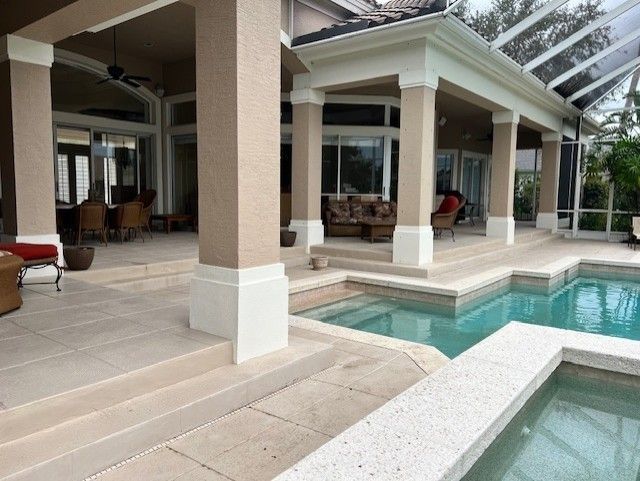 Patio with a pool and covered seating area, neutral colors.