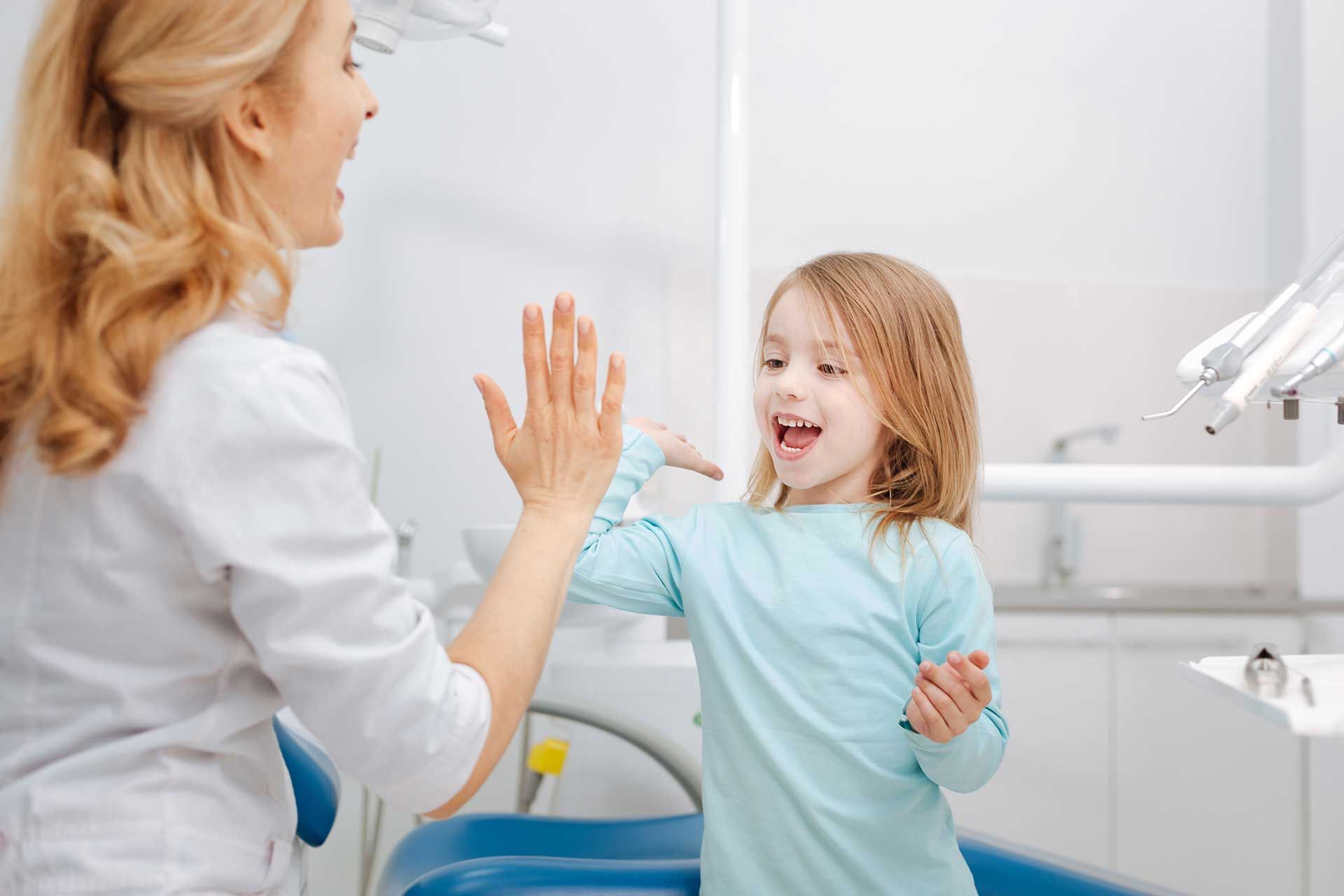 Dentist and smiling child giving a high-five in a bright dental clinic