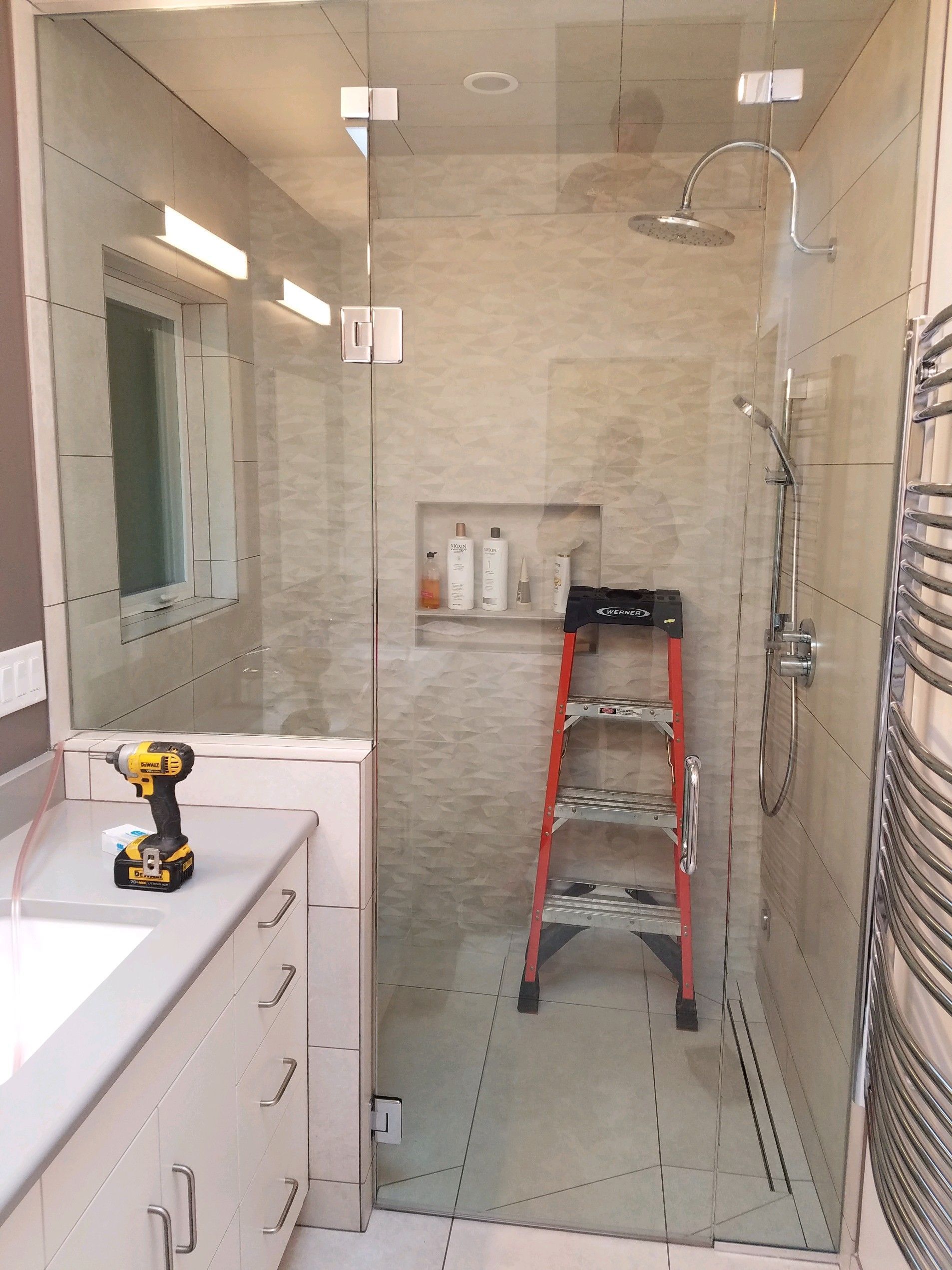 A bathroom with a walk in shower , sink , and ladder.