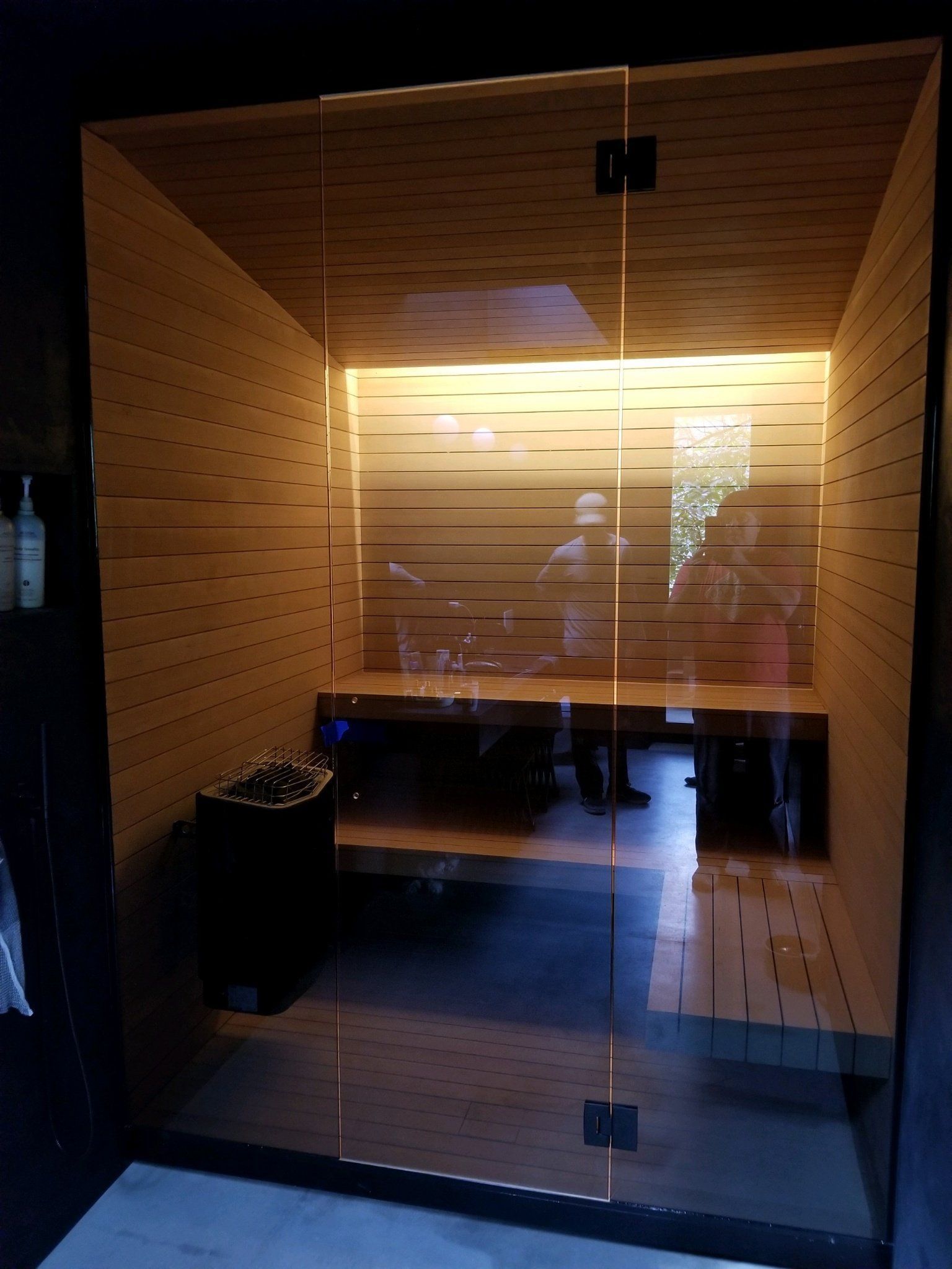A sauna with a glass door and wooden walls