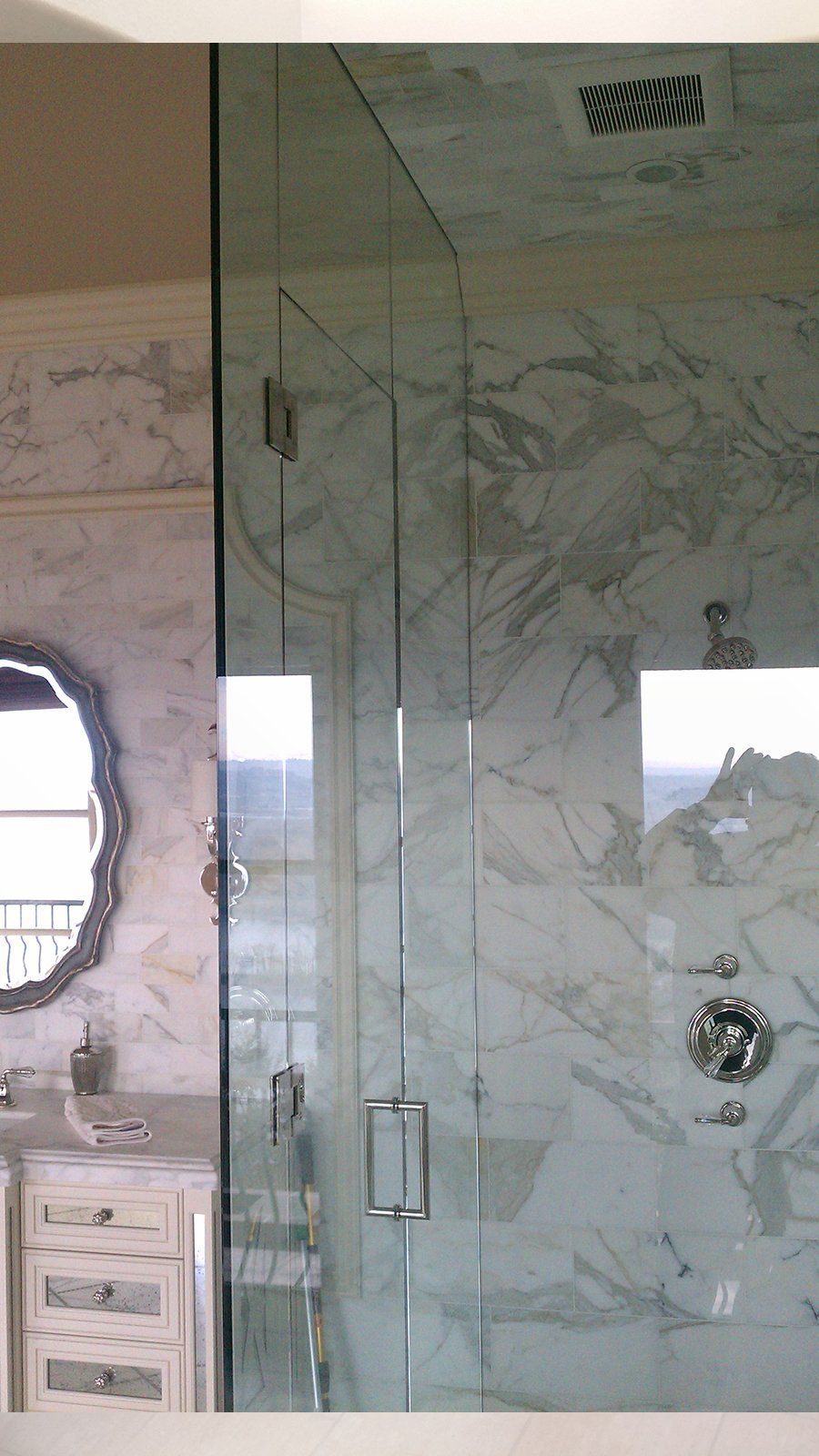 A bathroom with a glass shower door and a mirror
