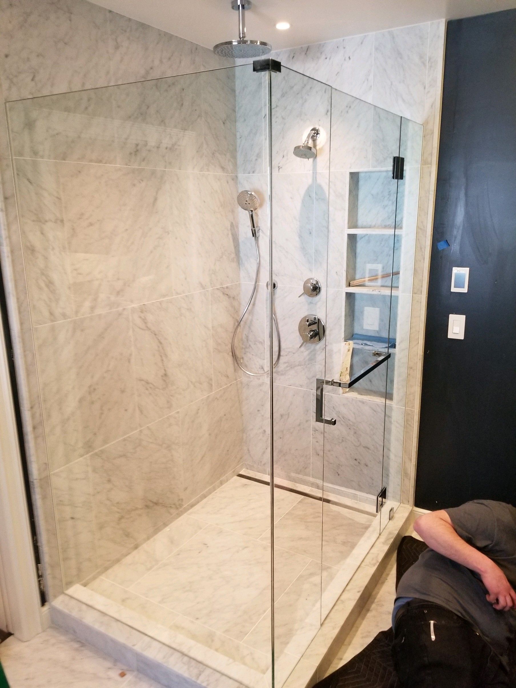 A bathroom with a walk in shower with a glass door.