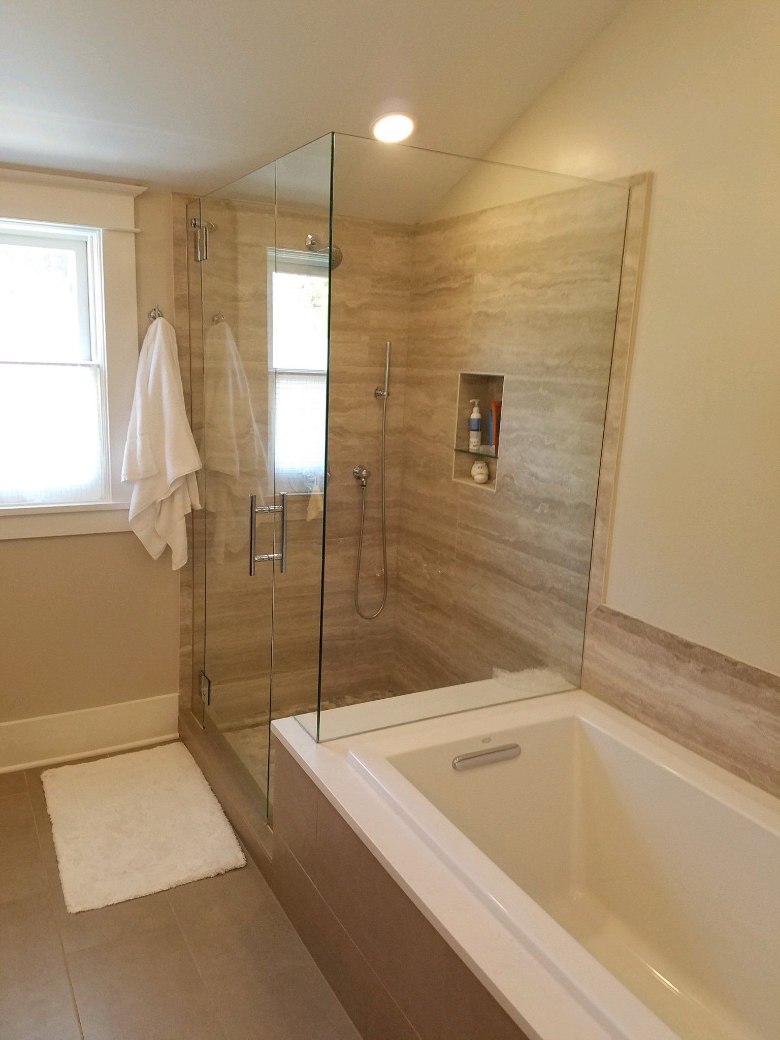 A bathroom with a tub , shower , and window.