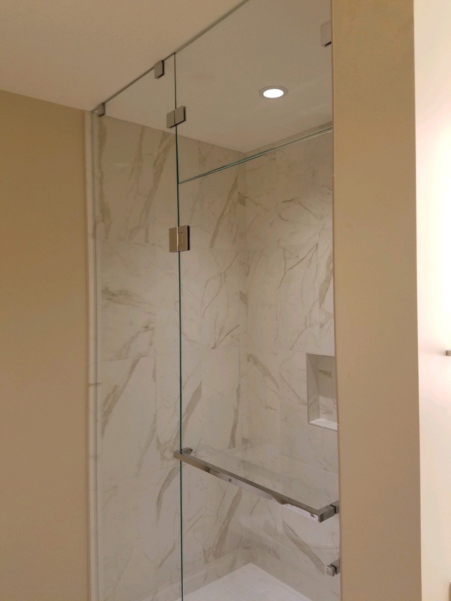 A bathroom with a walk in shower with a glass door.