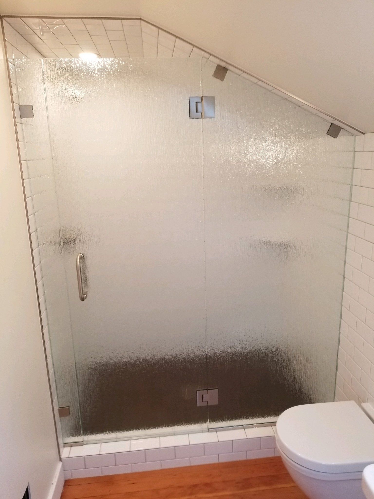 A bathroom with a glass shower door and a toilet.