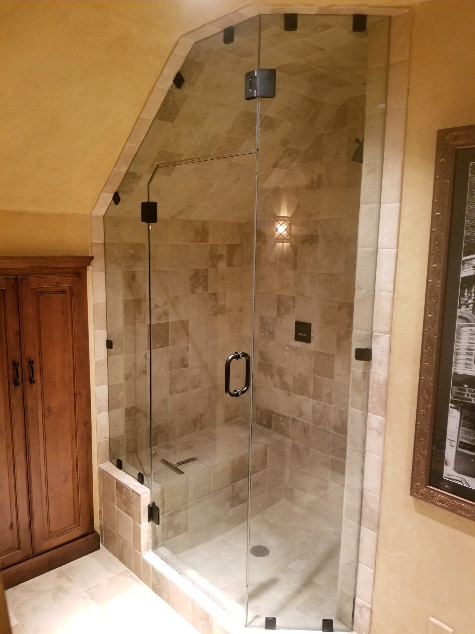 A bathroom with a walk in shower with a glass door.
