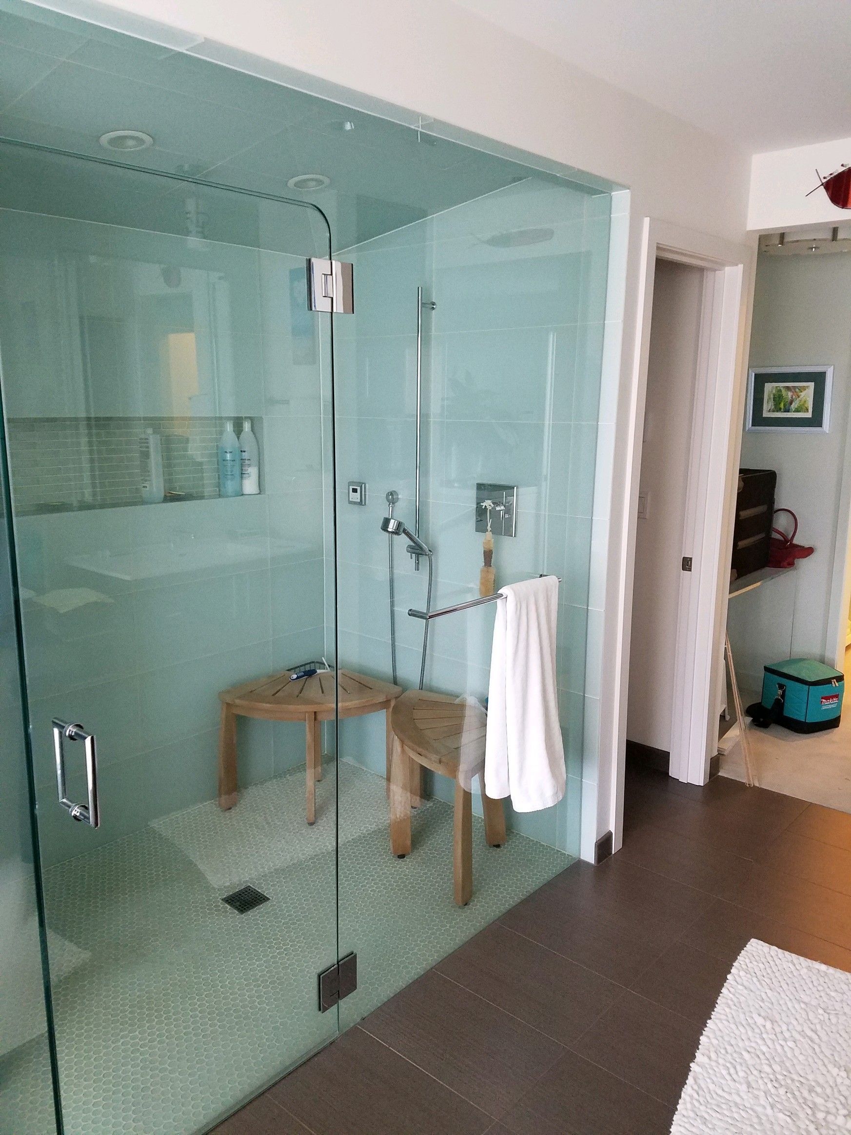 A bathroom with a walk in shower and a bench.