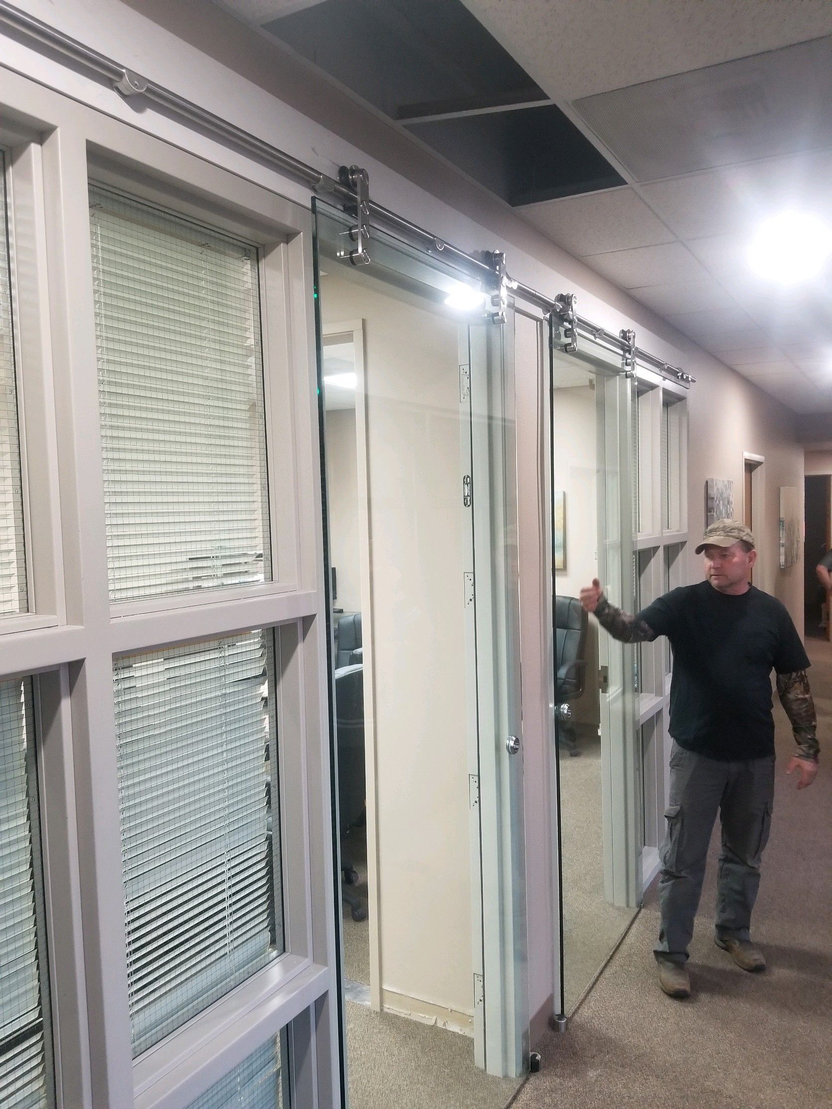 A man is standing in a hallway with sliding glass doors.