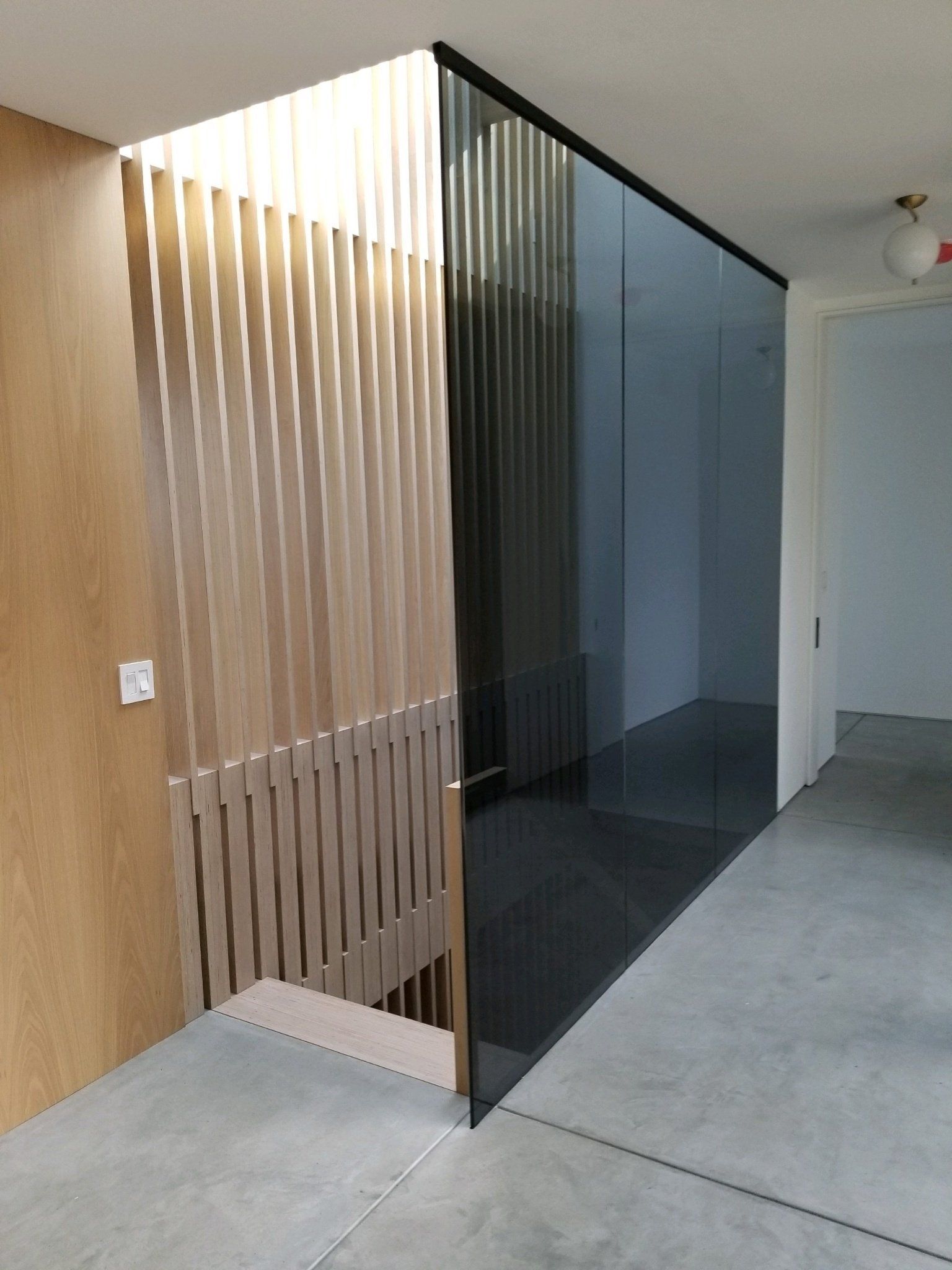 A hallway with a glass wall and a wooden divider