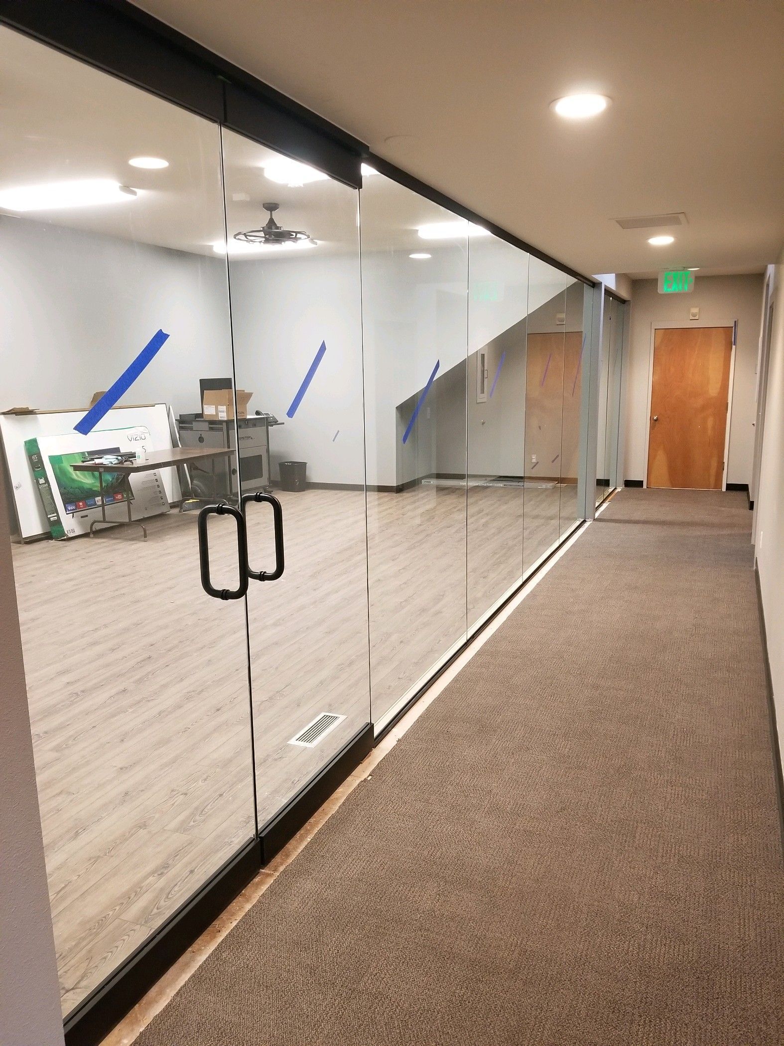 A hallway with a glass wall and a wooden door.