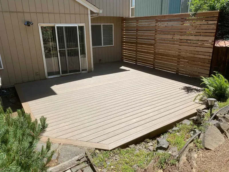 Wooden deck and privacy fence attached to a building with a sliding glass door.
