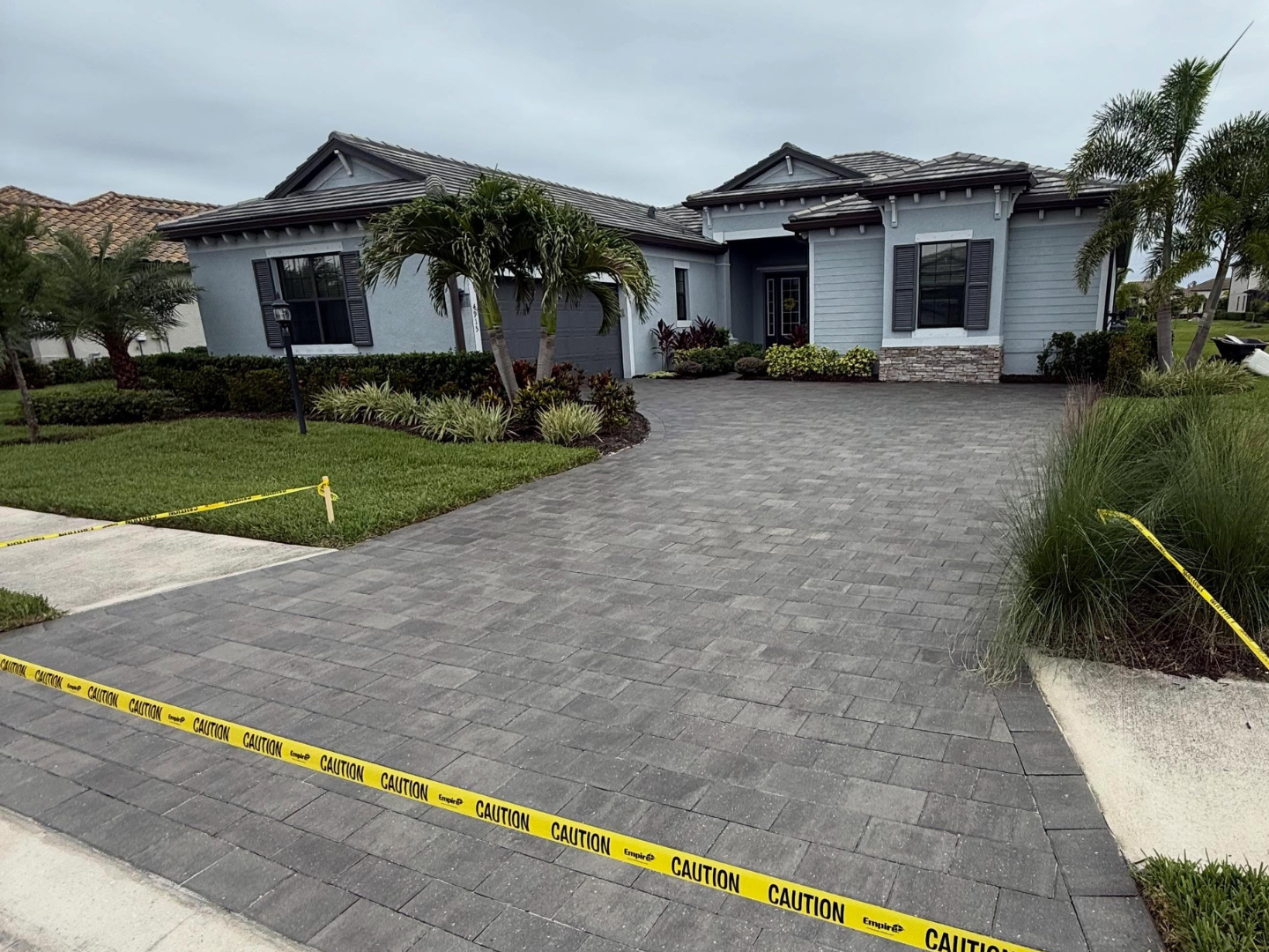 Suburban house with damaged driveway and yellow caution tape across the foreground