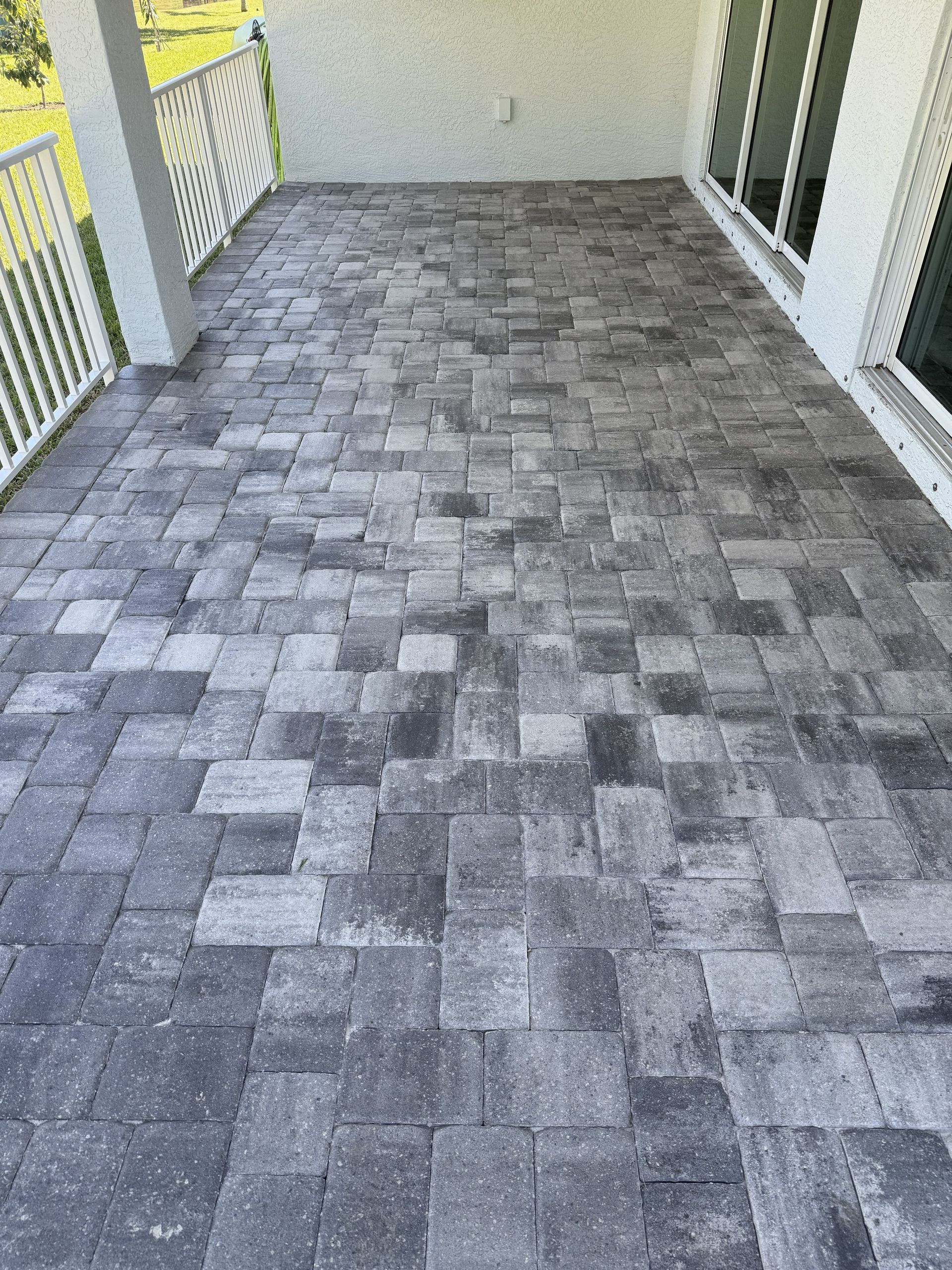 Gray paver-tiled walkway or patio with white railing and yellow walls