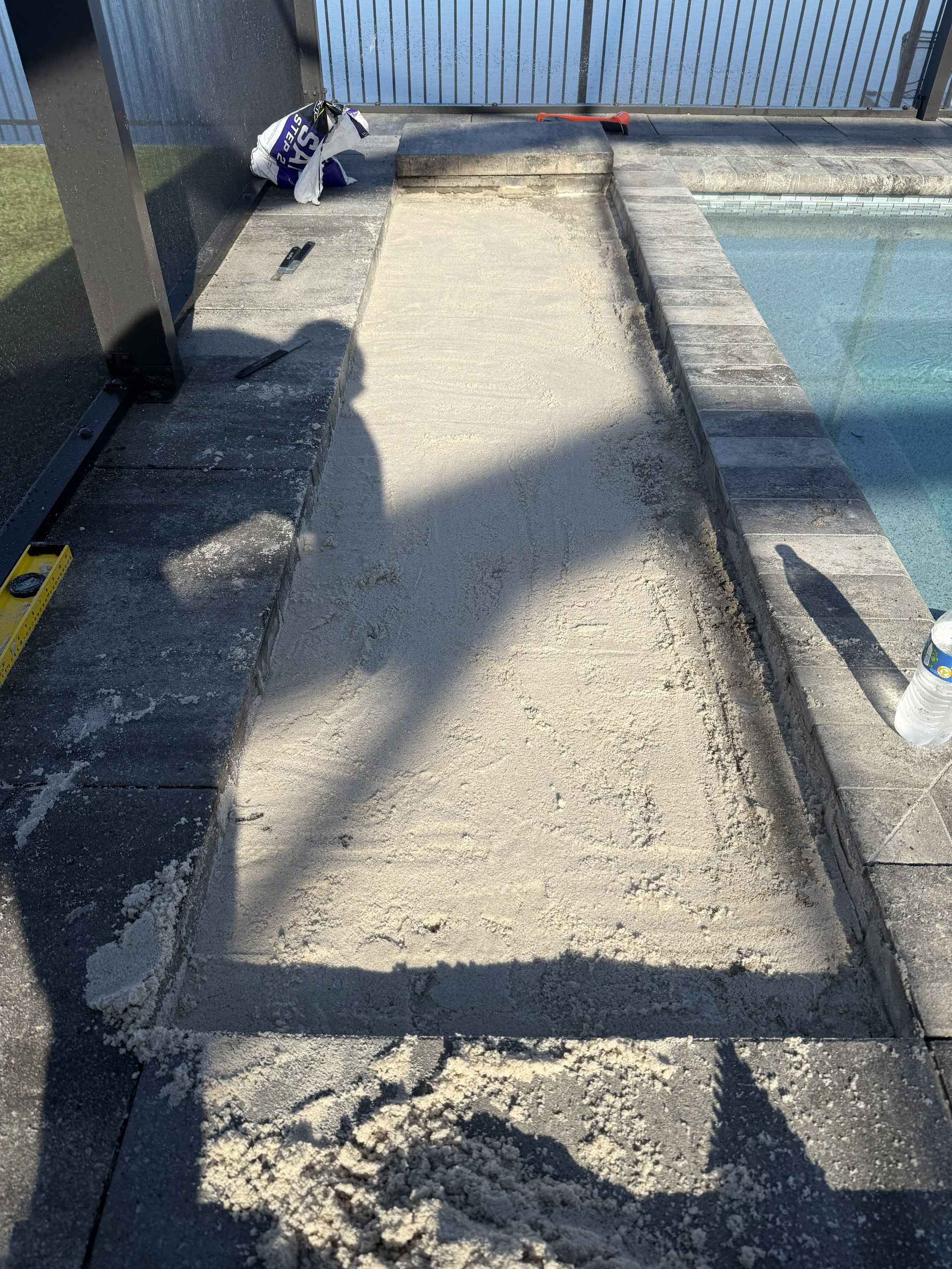 Damaged concrete poolside walkway with cracks and a blue pool on the right