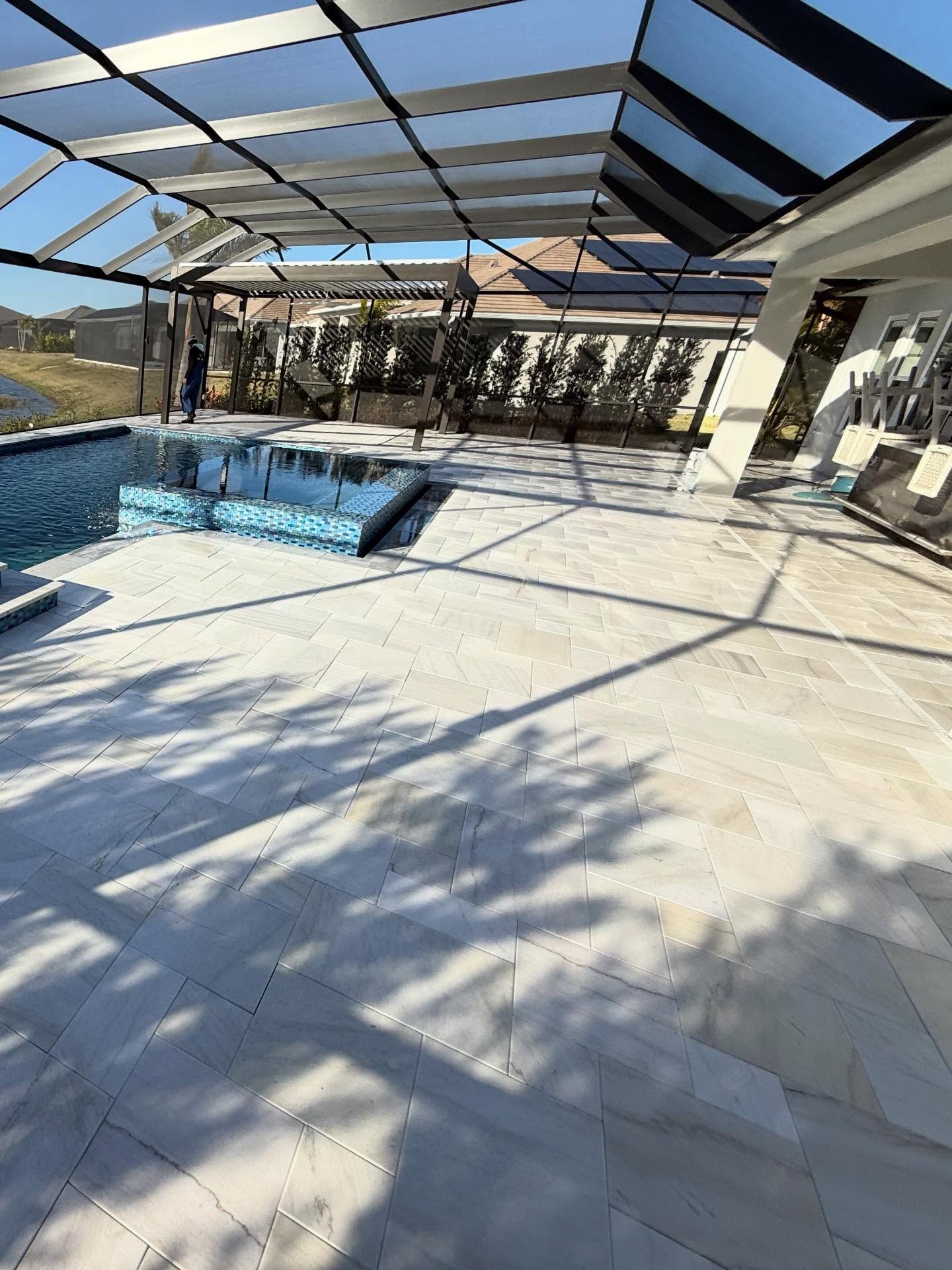Screened-in patio with a small pool, light tile floor, and sunlit beams casting shadows