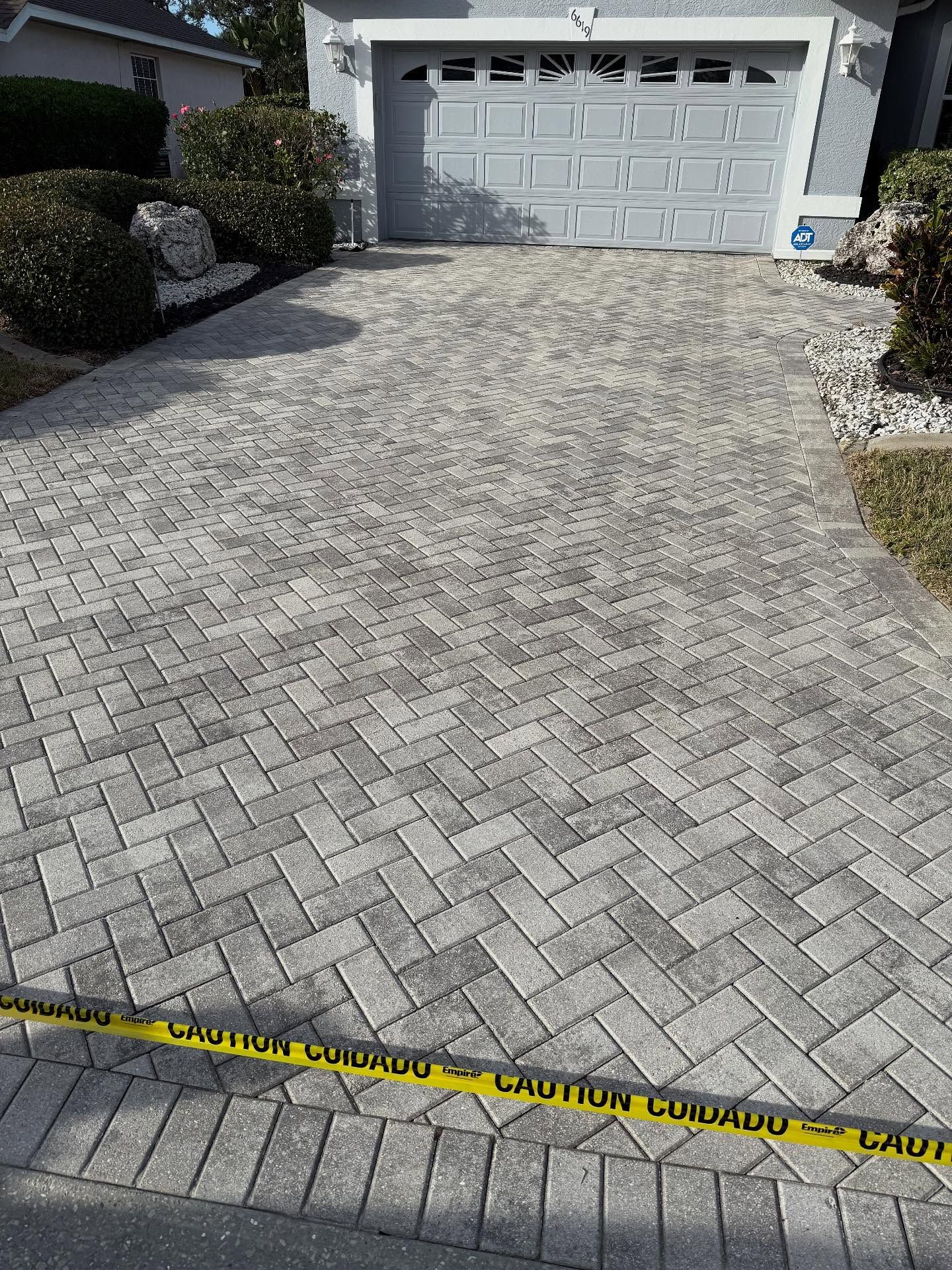 Driveway with decorative pavers leading to a garage, blocked off by yellow caution tape.