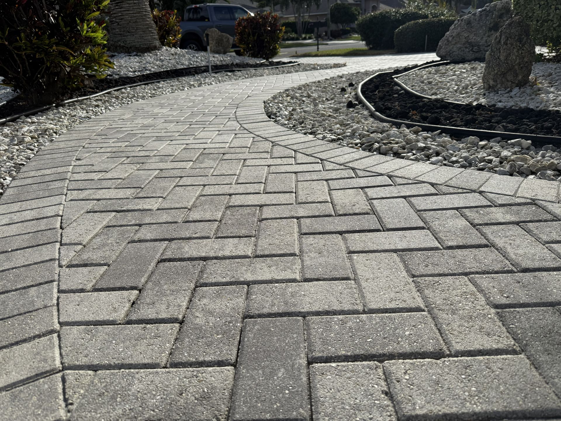 Curved stone-paver walkway through a landscaped garden with gravel and shrubs