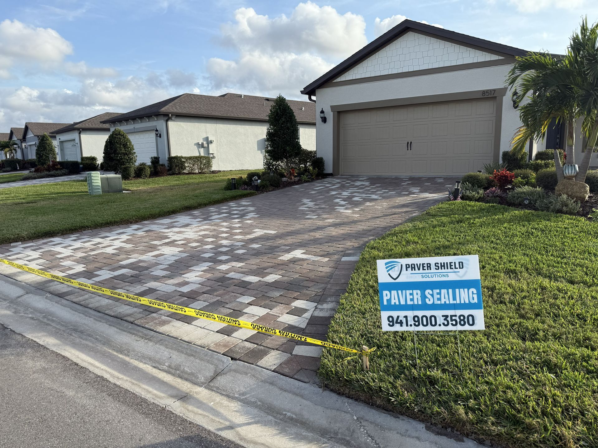 Suburban house with paved driveway and “For Sale” sign in front of garage
