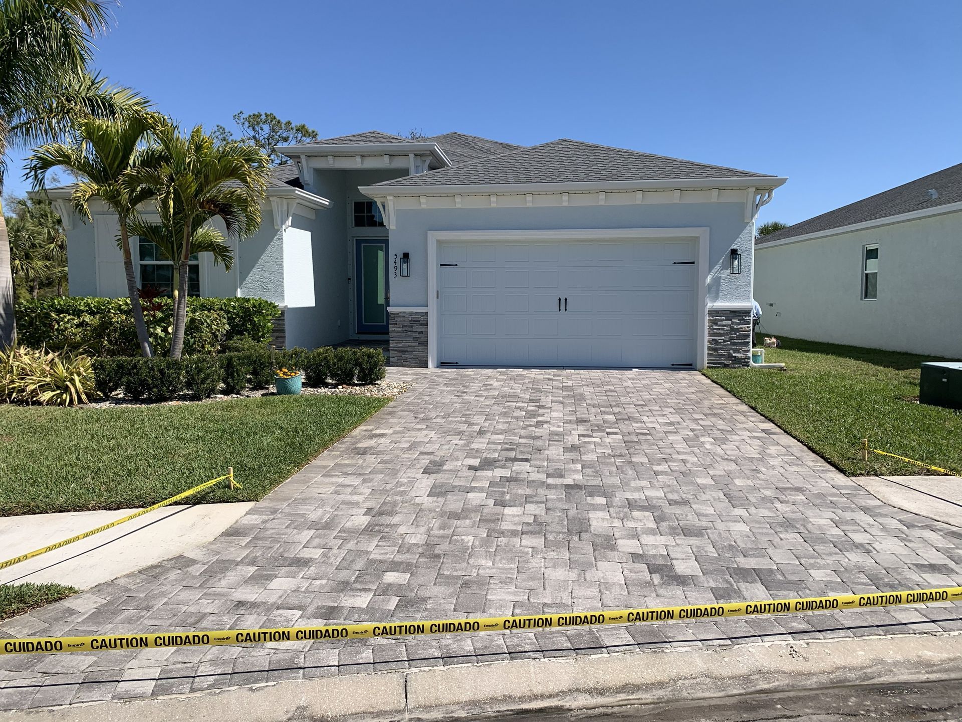 Single-story house with a white garage, stone driveway, and yellow caution tape across the front.