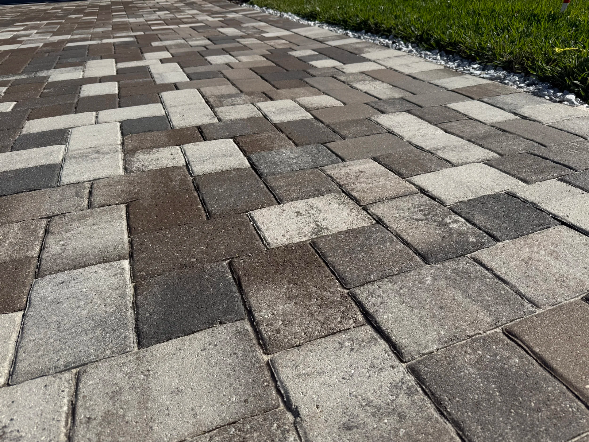 Interlocking gray and tan pavers forming a walkway, viewed at a low angle