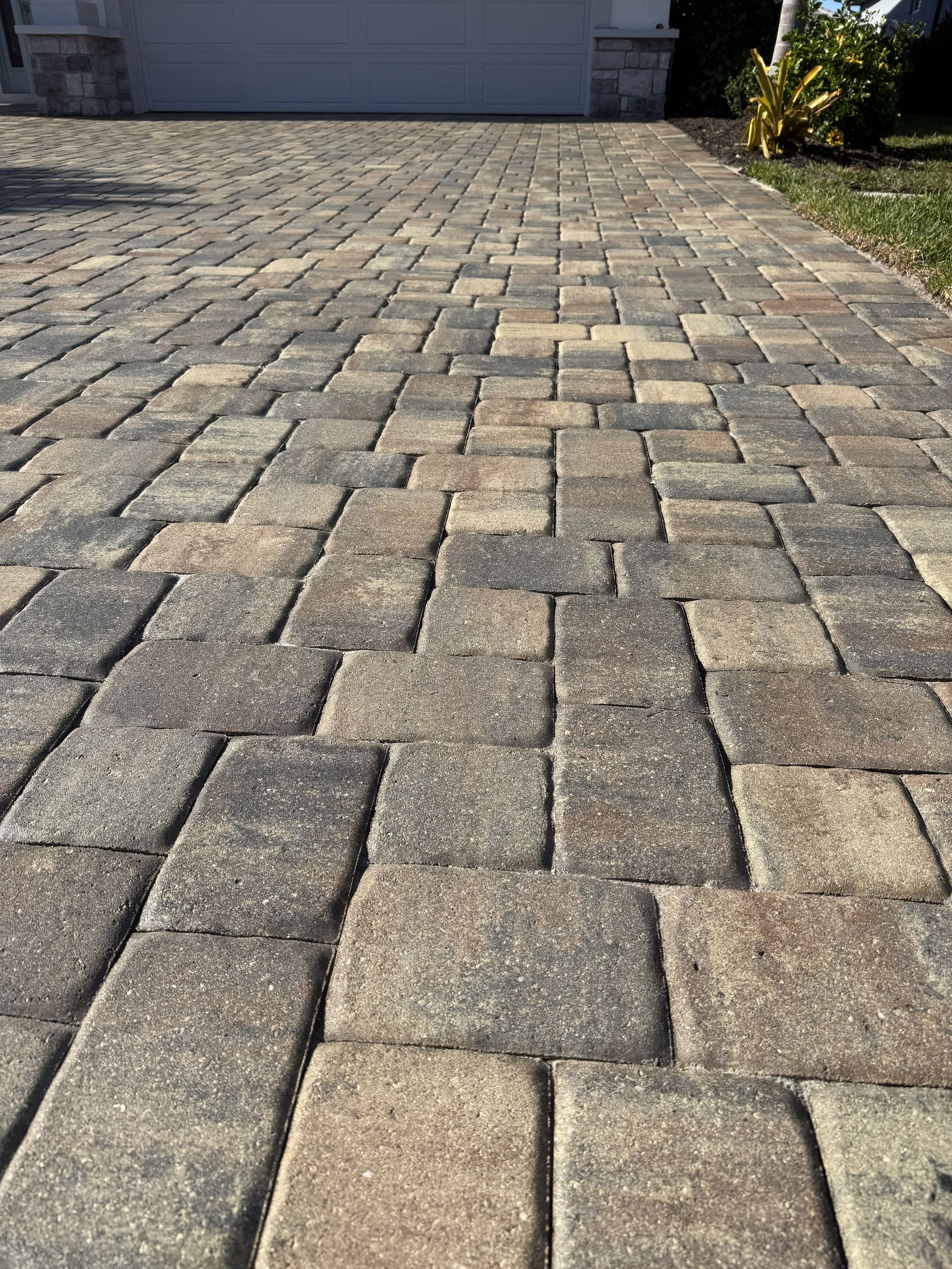 Stone-paved driveway with rectangular gray pavers leading to a house entrance.