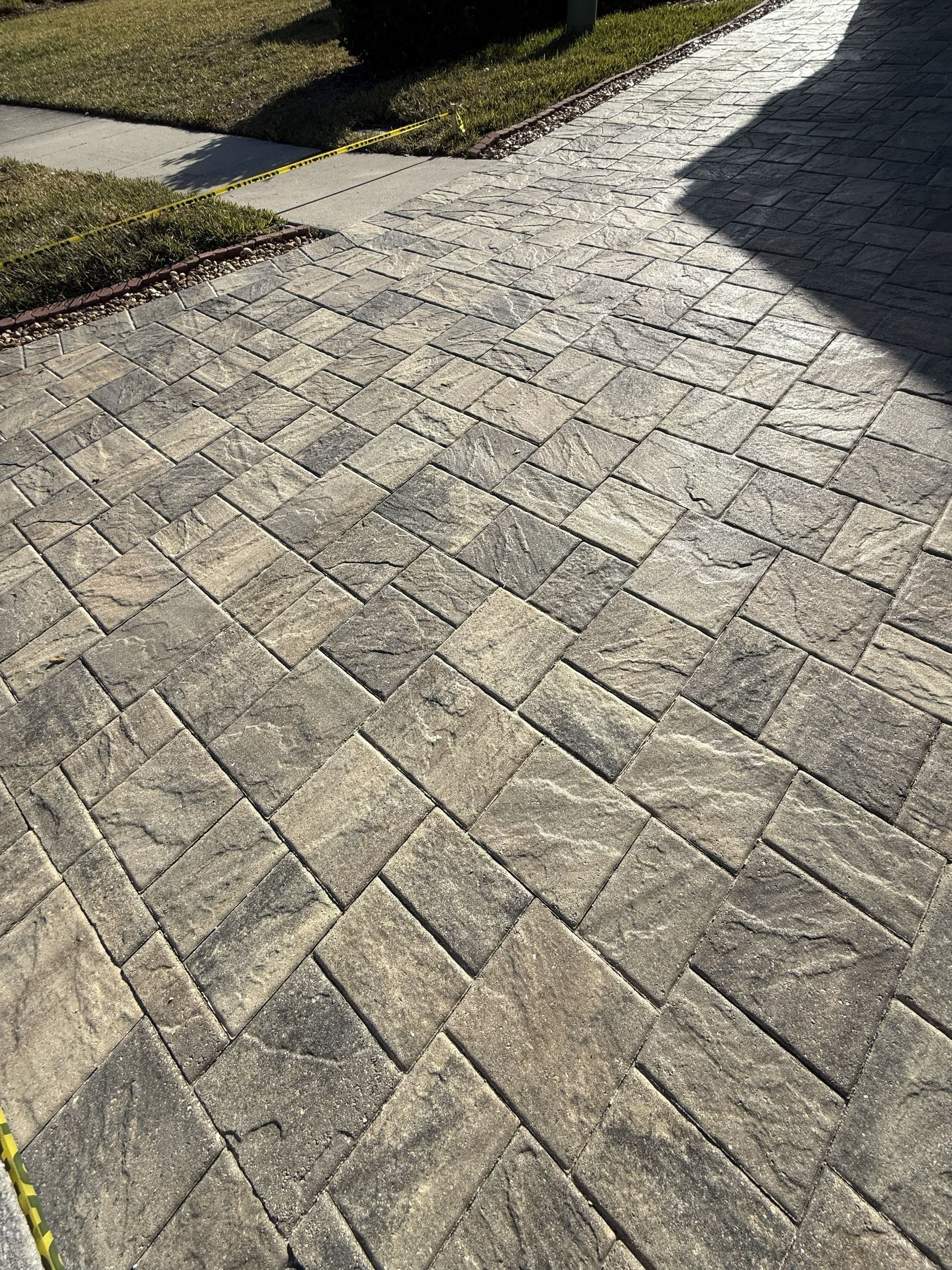 Stone-paved driveway curving past a grassy lawn in sunlight