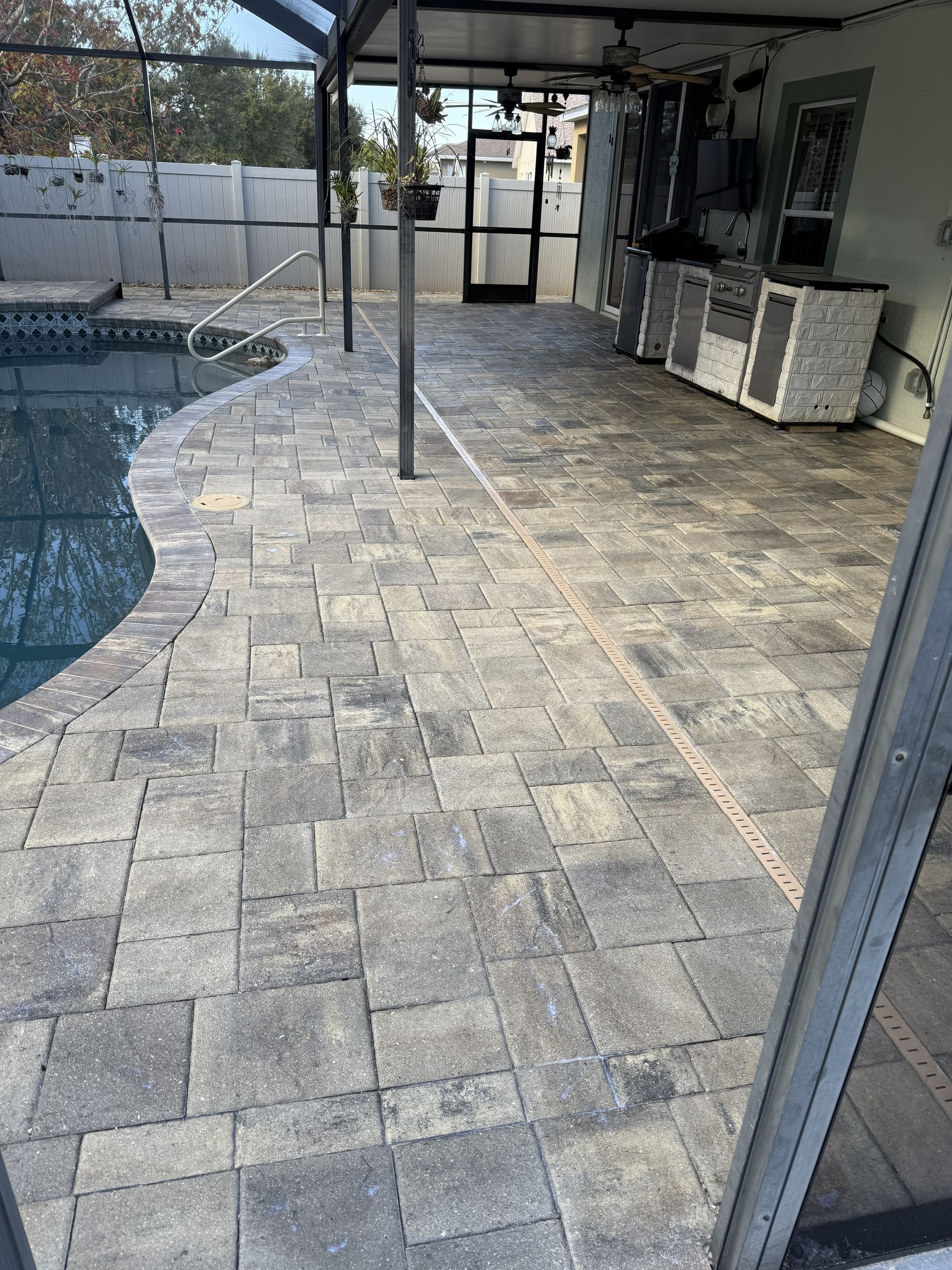 Stone pool deck with a patio umbrella and outdoor seating beside a swimming pool