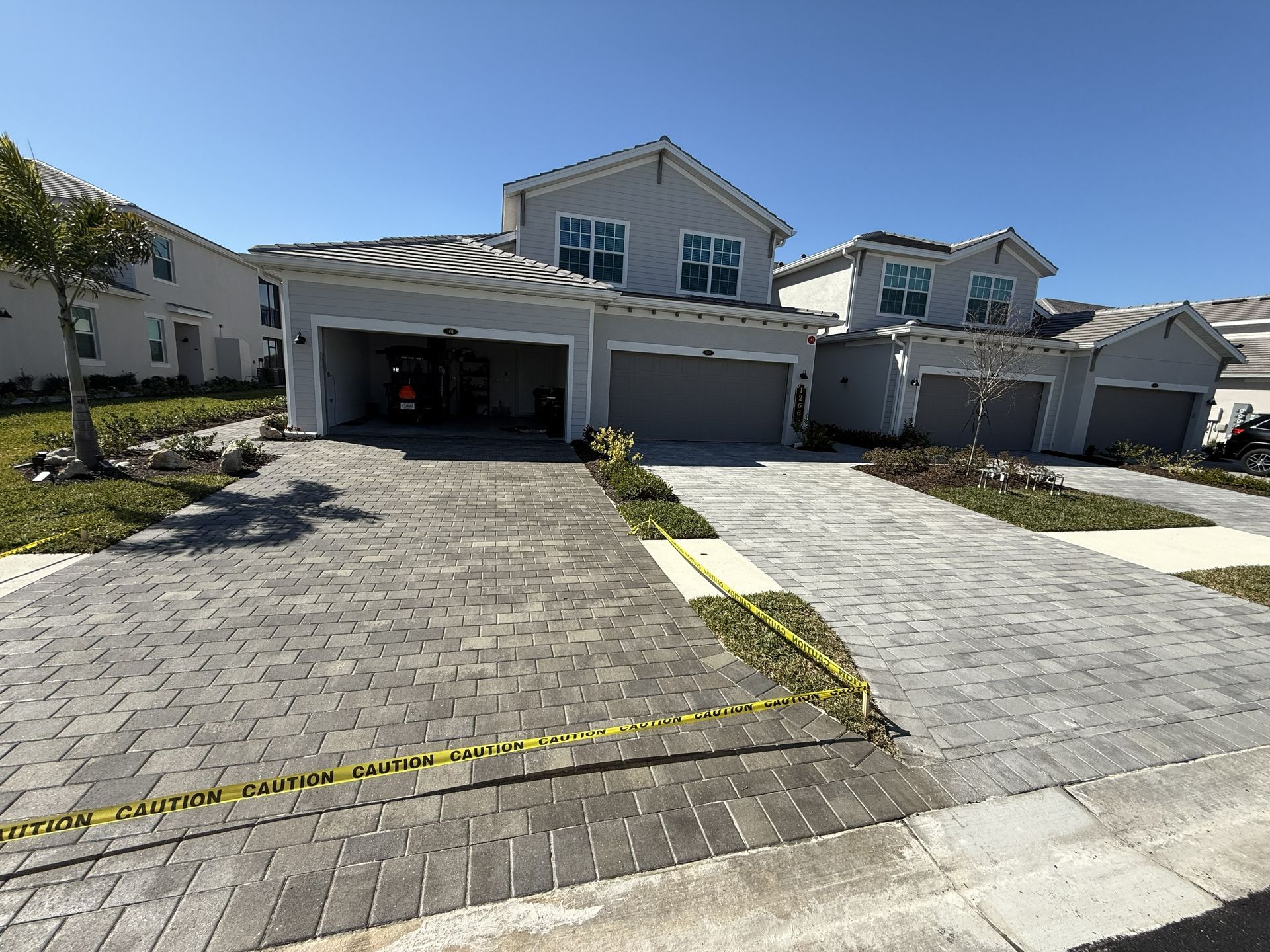 Two-story suburban house with open garage and paved driveway under a clear blue sky