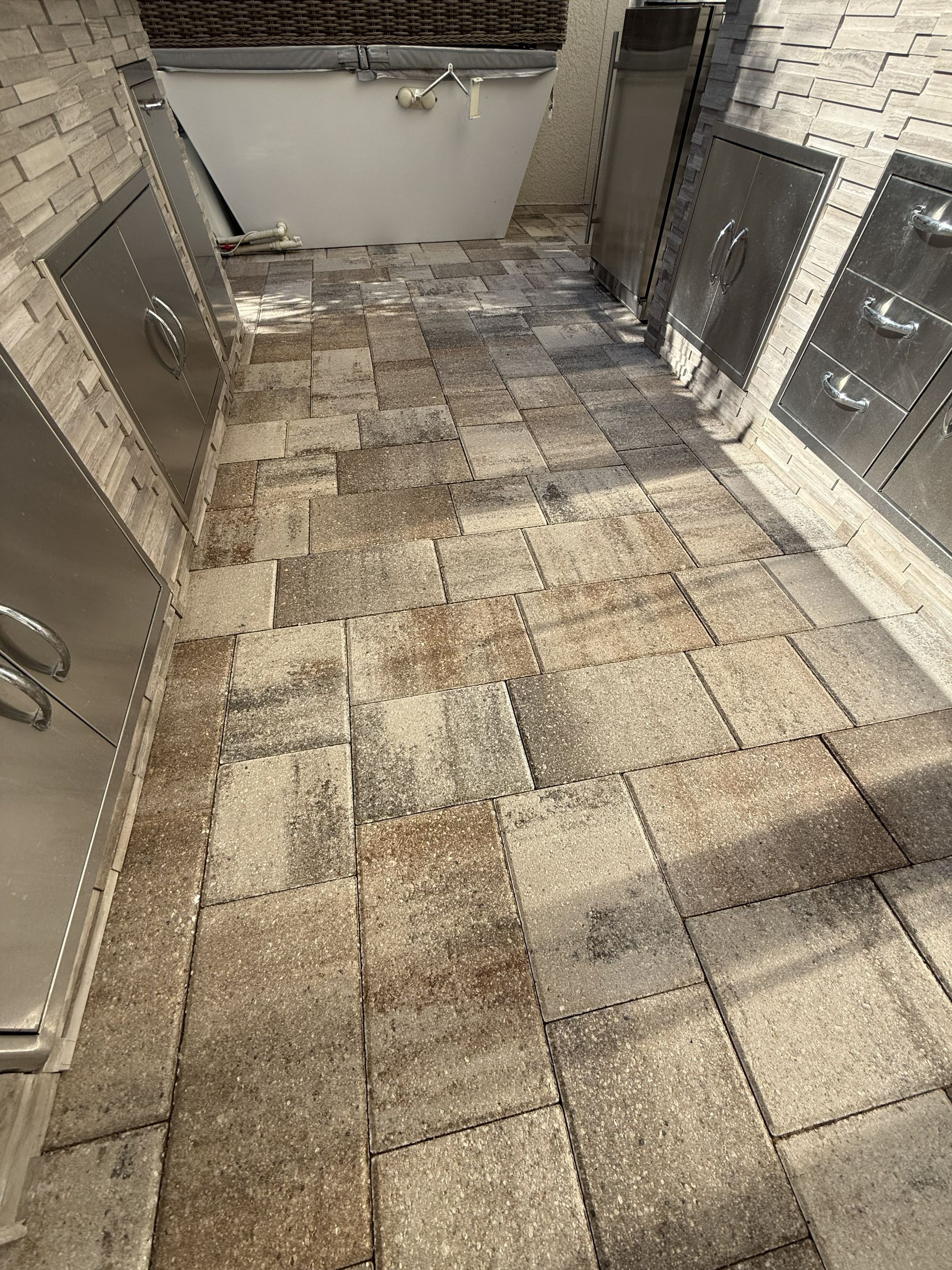Tiled patio or courtyard with stone floor, brick walls, and a white retaining wall at the end