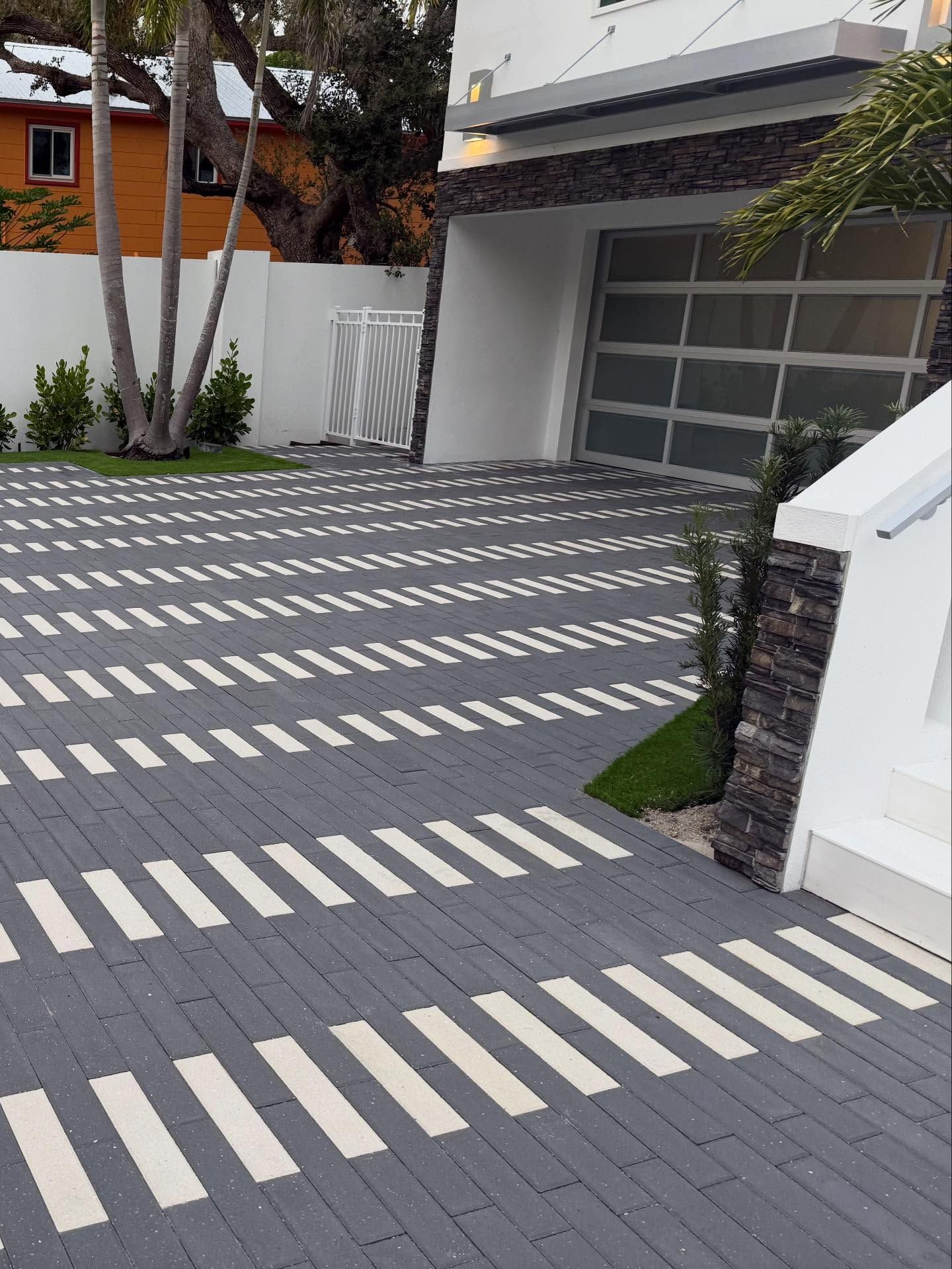 Modern house driveway with diagonal white-striped paving and garage door