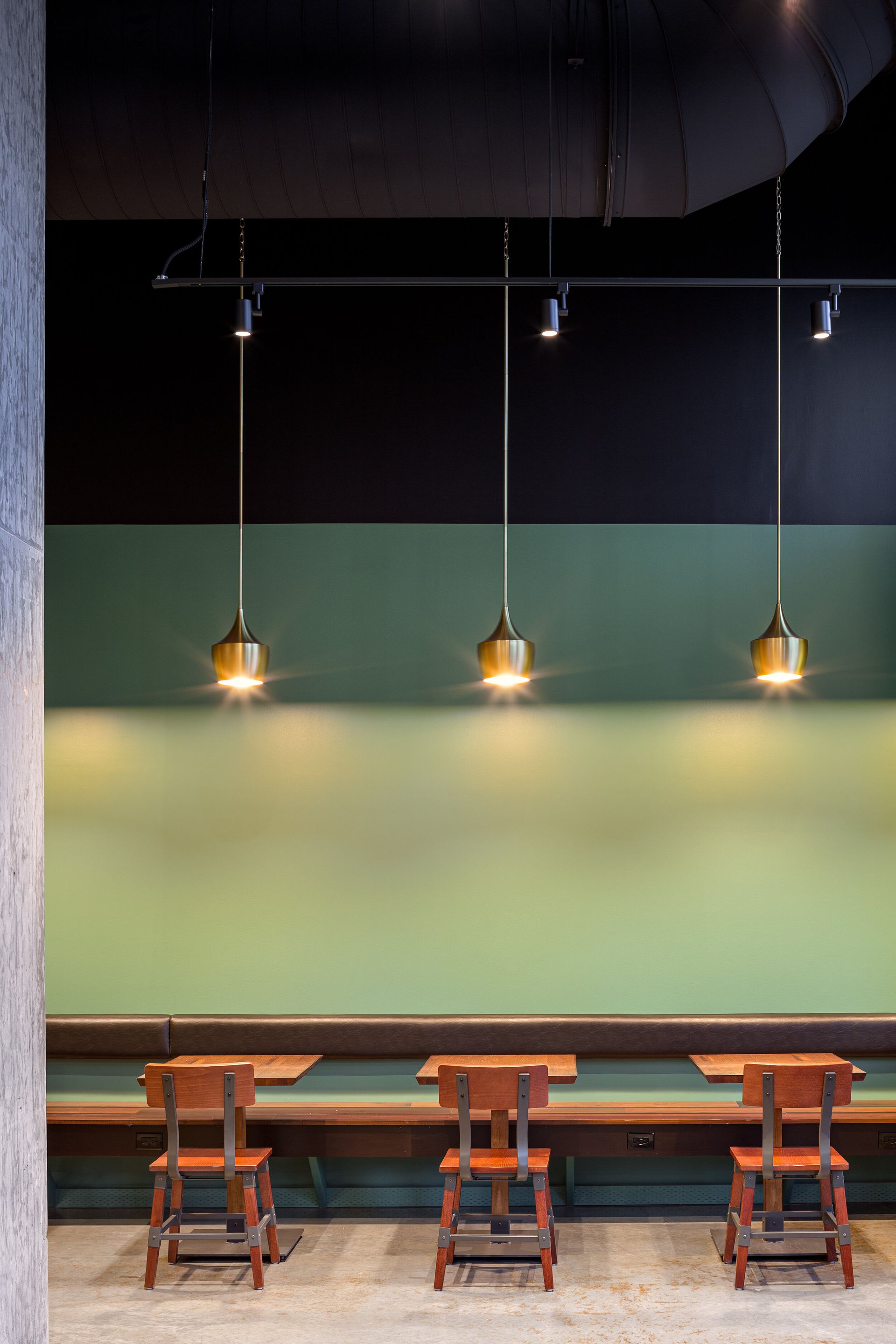 A restaurant with tables and chairs and a green wall.