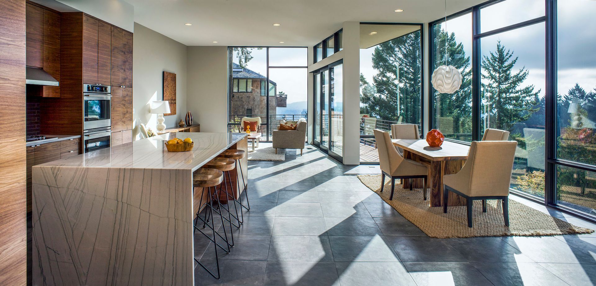A kitchen , dining room and living room in a house with lots of windows.