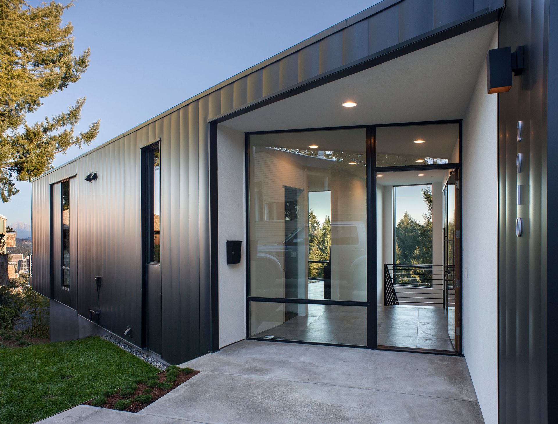 A modern house with a black siding and a large glass door