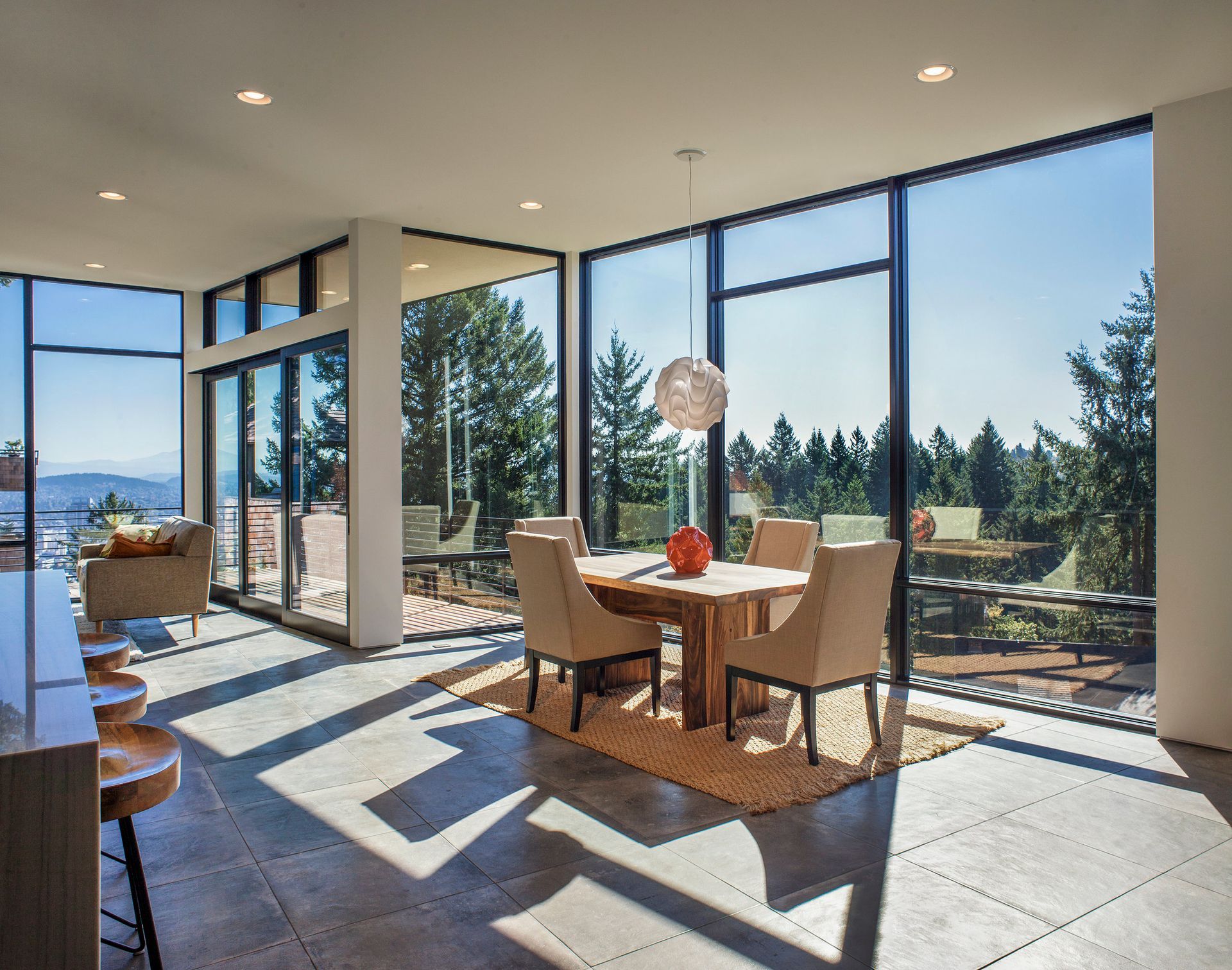A dining room with a table and chairs and a lot of windows.